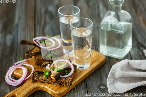 Image of Vodka and traditional snack on wooden background