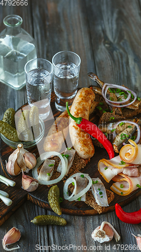 Image of Vodka and traditional snack on wooden background