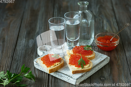 Image of Vodka and traditional snack on wooden background