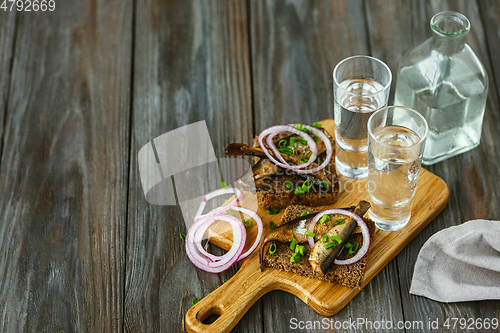 Image of Vodka and traditional snack on wooden background