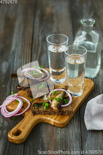 Image of Vodka and traditional snack on wooden background