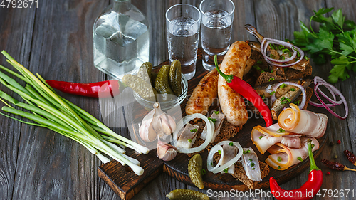 Image of Vodka and traditional snack on wooden background