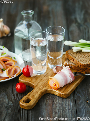 Image of Vodka and traditional snack on wooden background