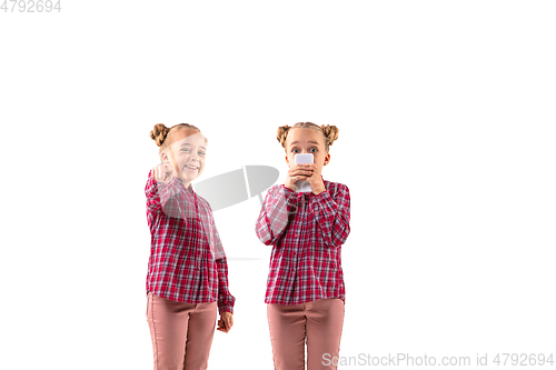 Image of Young handsome girl arguing with herself on white studio background.