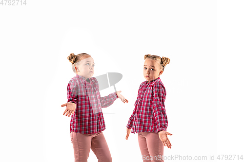 Image of Young handsome girl arguing with herself on white studio background.