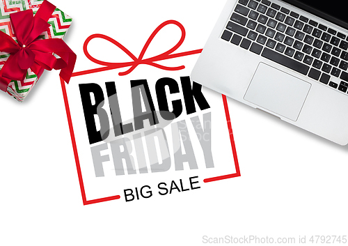 Image of Top view of laptop and present, gift with black friday lettering on white background