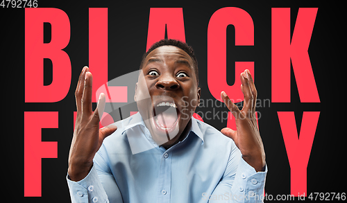 Image of Half-length close up portrait of young man on black background with black friday lettering