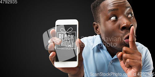 Image of Portrait of young man showing smartphone screen, black friday