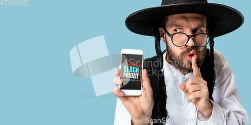 Image of Portrait of young man showing smartphone screen, black friday