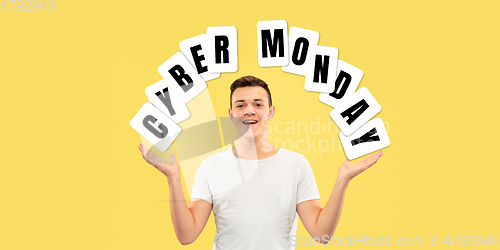 Image of Half-length close up portrait of young man on yellow background with cuber monday lettering