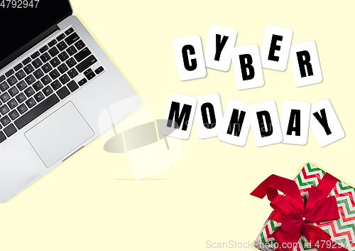 Image of Top view of laptop and present, gift with cyber monday lettering on yellow background