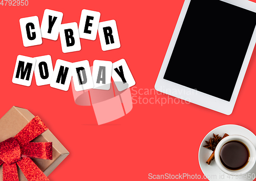 Image of Top view of tablet and present, gift with cyber monday lettering on red background