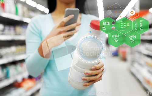 Image of woman with smartphone buying milk at supermarket