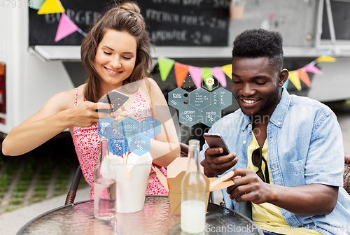 Image of couple with smartphones eating wok at food truck