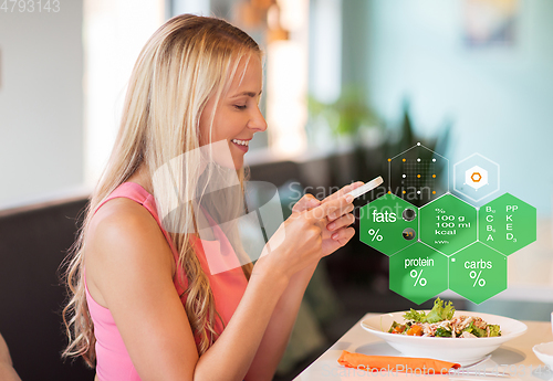 Image of happy woman with smartphone eating at restaurant