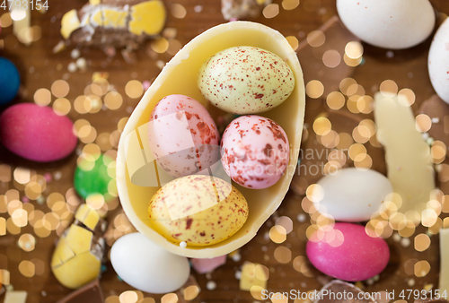 Image of chocolate egg and candy drops on wooden table