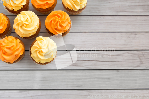 Image of cupcakes with frosting on wooden boards background