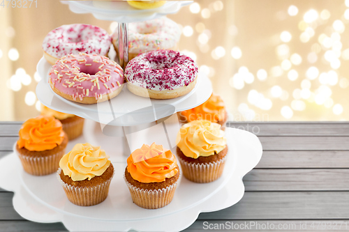 Image of glazed donuts, cupcakes with frosting on stand
