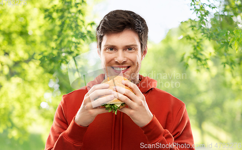 Image of happy young man eating hamburger