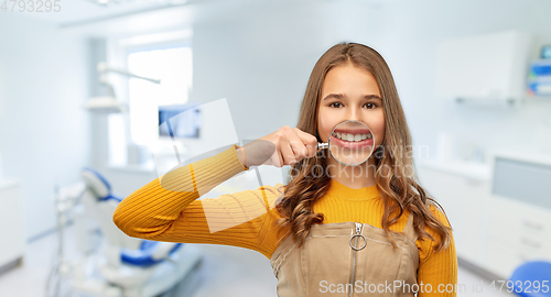 Image of girl with magnifier shows teeth at dental clinic