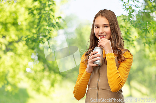 Image of happy teenage girl drinking soda from can