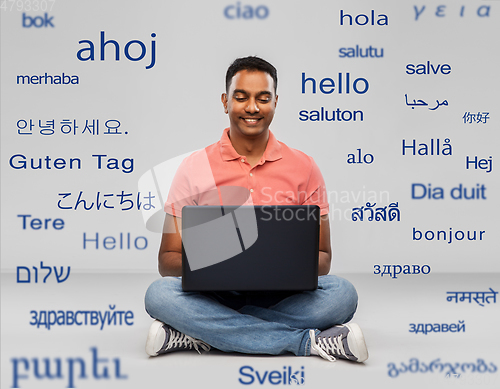 Image of happy indian man with laptop computer on floor