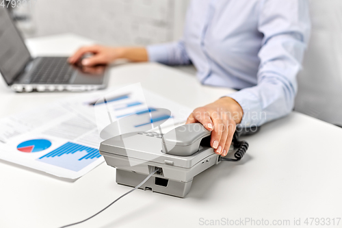 Image of businesswoman calling on desk phone at office