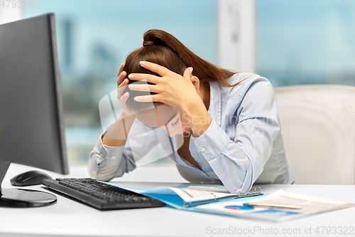 Image of stressed businesswoman with papers at office