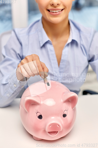 Image of businesswoman with piggy bank and coin at office