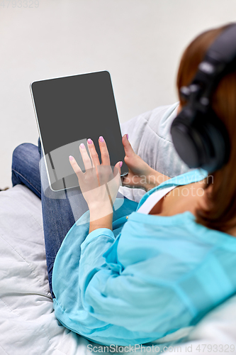 Image of woman with tablet pc and headphones at home