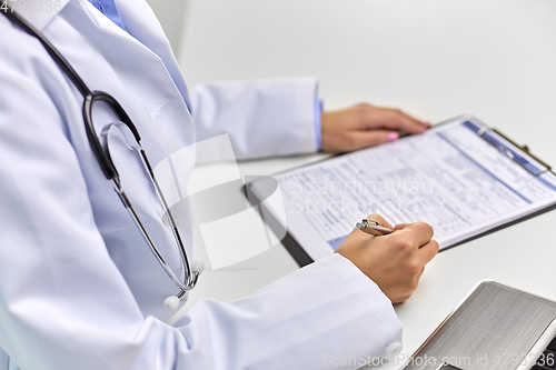 Image of close up of female doctor writing medical report