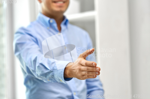 Image of smiling businessman making handshake at office