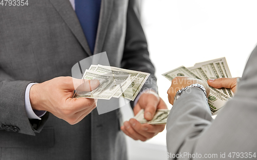 Image of close up of businessmen's hands holding money