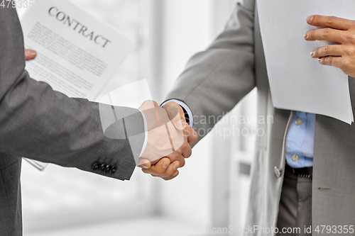 Image of close up of businessmen making handshake at office