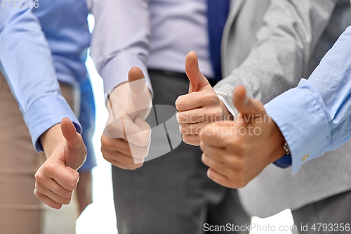 Image of close up of business team hands showing thumbs up