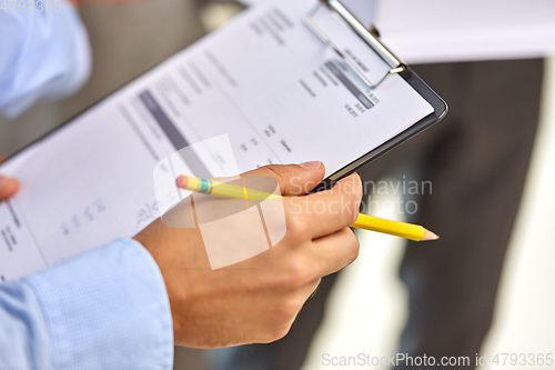 Image of hands of businessman holding clipboard with bill