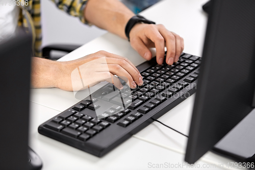 Image of male hands typing on computer keyboard on table