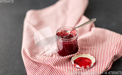 Image of mason jar with raspberry jam and spoon on towel