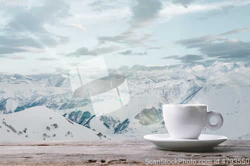 Image of Single tea or coffee cup and landscape of mountains on background