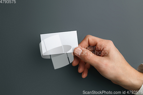 Image of Male hand holding a blank business card on grey background for text or design