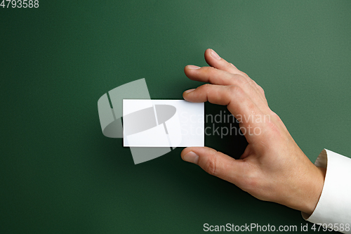 Image of Male hand holding a blank business card on green background for text or design