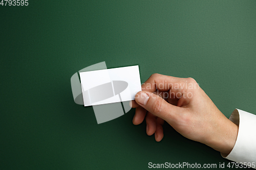 Image of Male hand holding a blank business card on green background for text or design