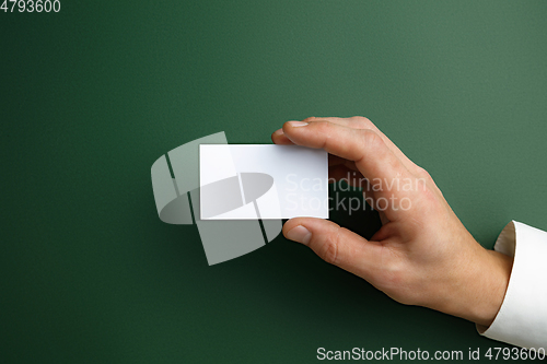 Image of Male hand holding a blank business card on green background for text or design
