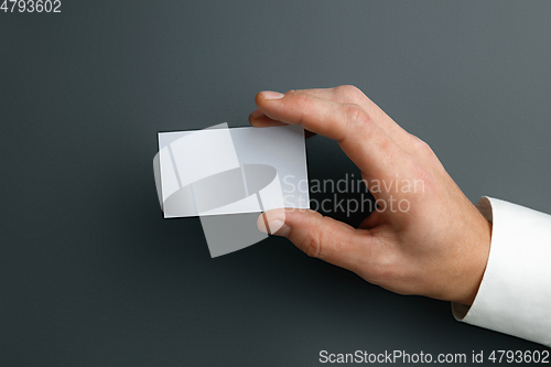 Image of Male hand holding a blank business card on grey background for text or design