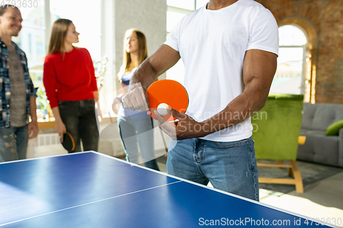 Image of Young people playing table tennis in workplace, having fun