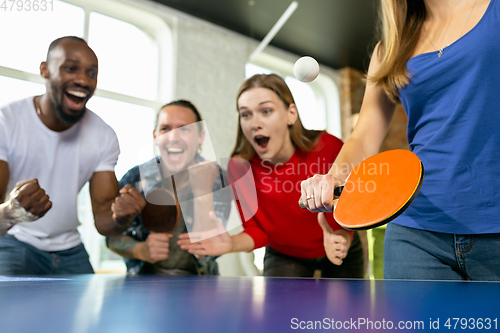 Image of Young people playing table tennis in workplace, having fun