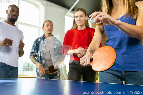 Image of Young people playing table tennis in workplace, having fun