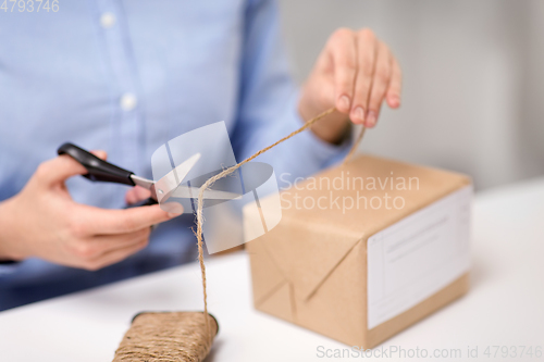 Image of woman with parcel cutting rope at post office