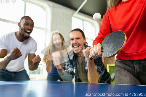 Image of Young people playing table tennis in workplace, having fun