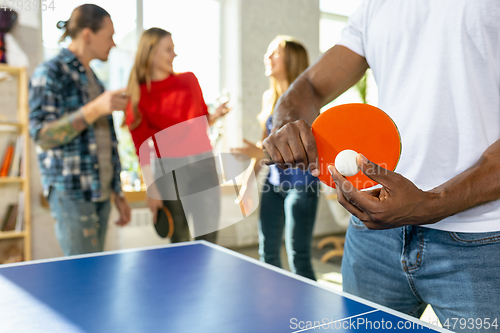 Image of Young people playing table tennis in workplace, having fun